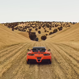 an orange sports car sits on a dirt road in a wide - open field