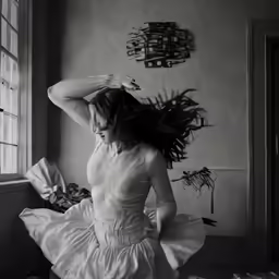 woman in dress dancing against wall with wall art