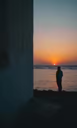 silhouette of man standing at beach as the sun sets