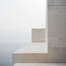 an empty sidewalk that has a white stone wall and stairs