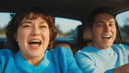 a couple sitting inside of a car with their mouths open