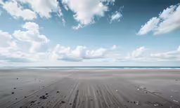a beach scene with a vast blue sky filled with white clouds