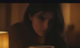 a girl drinking coffee on her bed, in the dark