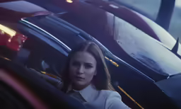 a woman is driving a red car in the rain