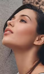 a woman with her hair up is leaning on a wall and looking at the side