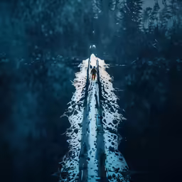a couple on a pier in the middle of the lake with snow on the ground