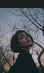 a woman looking up with her head up against trees