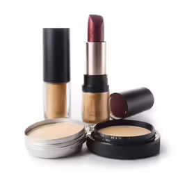 makeup is arranged on white surface, including lipstick and foundation