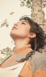 the girl is staring up by the tree