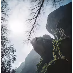 a man on a cliff reaching up into the sky