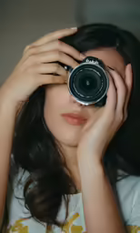 the woman holds her camera in front of her face