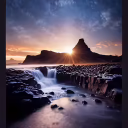 a water fall near some mountains during a sunset