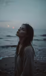a woman standing on the shore looking up at the sky