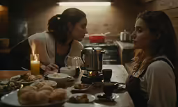 a couple of women sitting at a wooden table eating