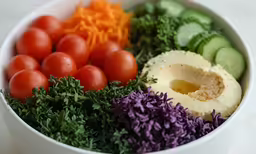 a bowl with carrots, cucumbers and tomatoes