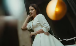 a beautiful woman wearing a wedding dress standing by the wall