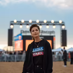a woman posing for a picture in front of an empty field