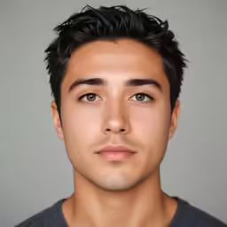 an attractive young man with short hair wearing a blue shirt