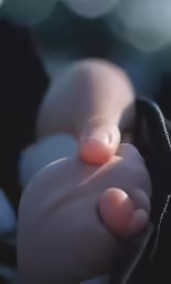 the baby has his finger touching the wrist of his parent