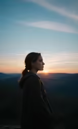 a woman stares into the distance at sunset