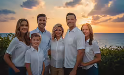 family in white shirts standing in front of the ocean at sunset