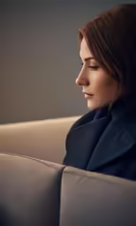 a woman sitting on a couch in front of a grey wall