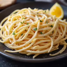 a plate that has noodles with sauce and a lemon