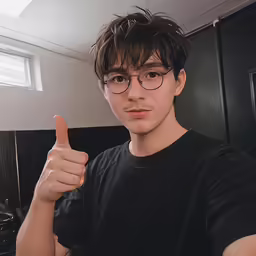 young man making thumbs up while wearing glasses in a kitchen