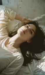 woman laying down on a bed with white sheets