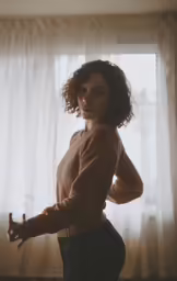 a woman standing in front of a window with her arms out