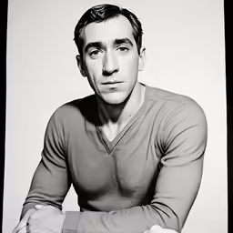 a man in sweater and jeans poses for a photo