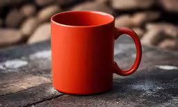an orange mug sits on a piece of stone