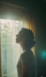 a beautiful young woman standing in front of a window