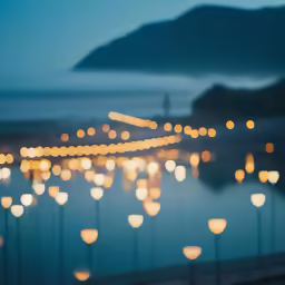 many candles are lit up on the water in this nighttime scene