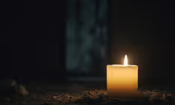 an illuminated candle sitting on the ground in the dark