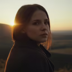 a woman looks into the distance at sunset in a photo