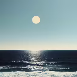 a full moon shines in the distance over the ocean