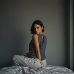 a woman sits on a bed posing for a portrait