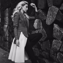 a woman posing against a wall in front of rocks