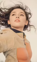 a woman standing in the grass holding her head in the wind