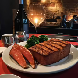 meat is on a plate and a wine glass is next to it