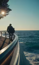 a person walking on a side walk looking at the ocean
