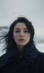 a young woman is posing outdoors with the snow on her face