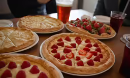 various pizzas and pie plates with strawberries on them