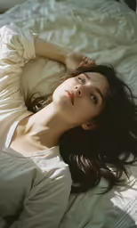 a woman laying on top of a white bed