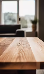 a wooden table in front of a window next to a couch