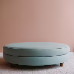 a round ottoman on an all white rug