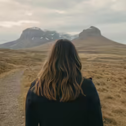 a woman walking towards the mountain range with her back to her camera