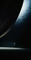 a man stands beneath a very large umbrella in the dark