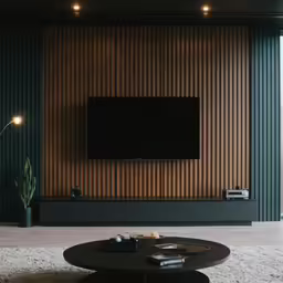 a large flat screen tv mounted on a green wall next to a black table